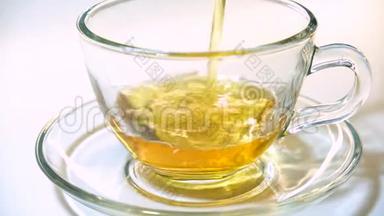 在白色背景特写镜头上，将茶壶中的红茶香气注入一个匹配的透明<strong>玻璃茶杯</strong>。